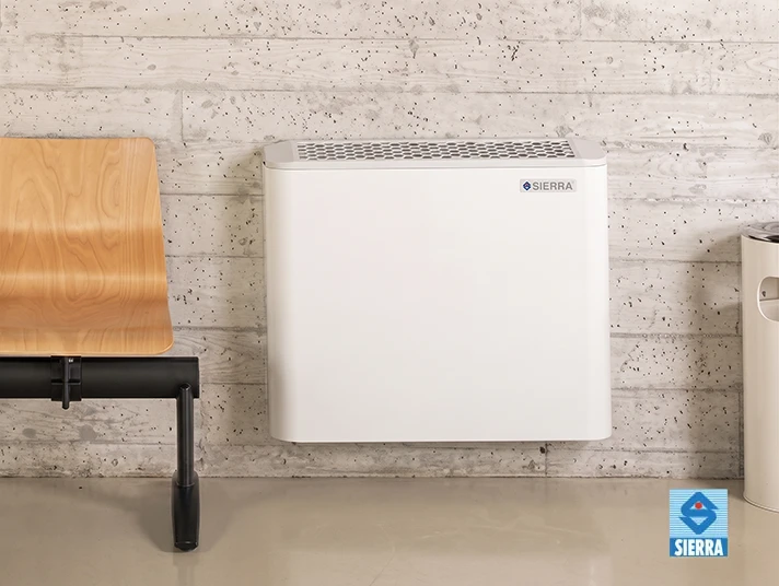 Sierra white wall-mounted climate unit on a raw concrete wall beside a plywood bench